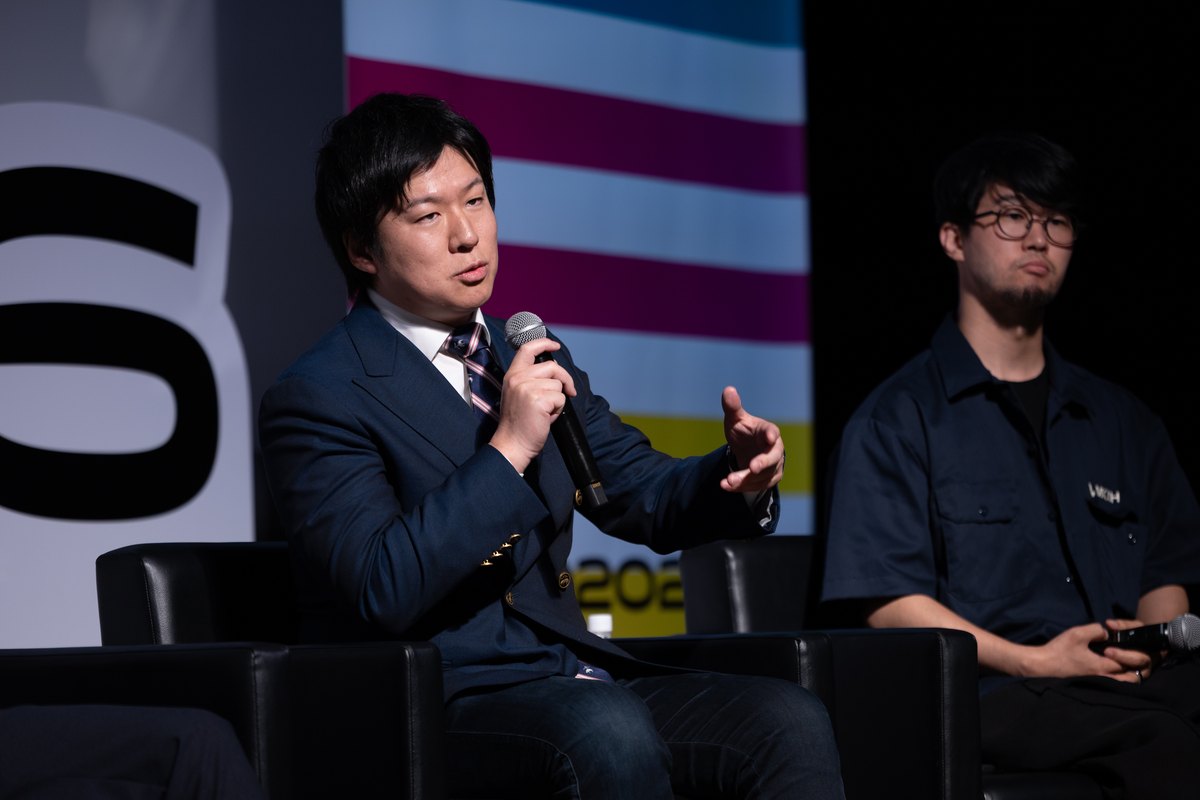 ステージで対談する2名。ひとりがマイクを持って話している